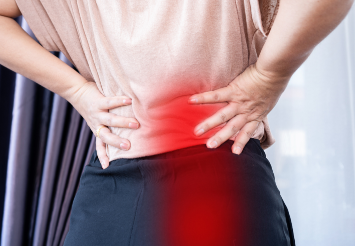Femme posant les mains sur le bas de son dos, avec une zone rouge indiquant une douleur irradiant vers la jambe, illustrant les bienfaits du shiatsu pour soulager les douleurs liées au nerf sciatique - Cabinet Terre de Shiatsu Lyon 5e