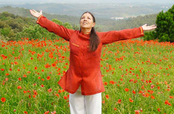 Monserrat Gascon souriant avec le regard et les bras ouverts tournés vers le ciel dans un champ de coquelicots qui illustre l'harmonie corps-esprit - cabinet Terre de Shiatsu Lyon 5e