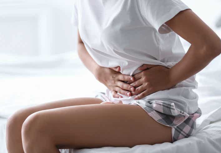 Image d’une femme assise sur un lit, tenant son bas-ventre avec les mains, illustrant les douleurs liées à l’endométriose, apaisées par un massage thérapeutique proposé par le cabinet Terre de Shiatsu Lyon 5e.