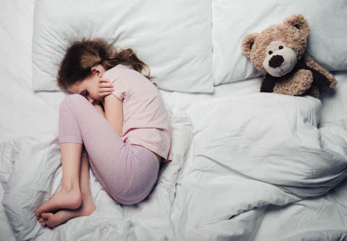 Petite fille recroquevillée dans son lit, signe de troubles du sommeil liés à l’anxiété — massage Shiatsu apaisant au cabinet Terre de Shiatsu Lyon 5e.