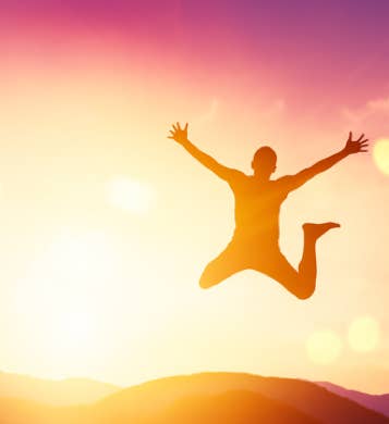 Une personne pleine de vitalité qui saute dans un décor de coucher de soleil en contre-jour en montagne – cabinet Terre de Shiatsu Lyon 5e