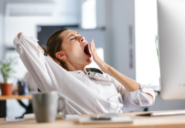Femme fatiguée bâillant devant son ordinateur dans un bureau en pleine journée, exprimant un épuisement physique et mental. Cette image illustre la fatigue chronique liée au stress ou au manque de sommeil, et souligne l’intérêt d’un massage sommeil au cabinet Terre de Shiatsu Lyon 5e pour restaurer l’énergie et favoriser une récupération en profondeur.