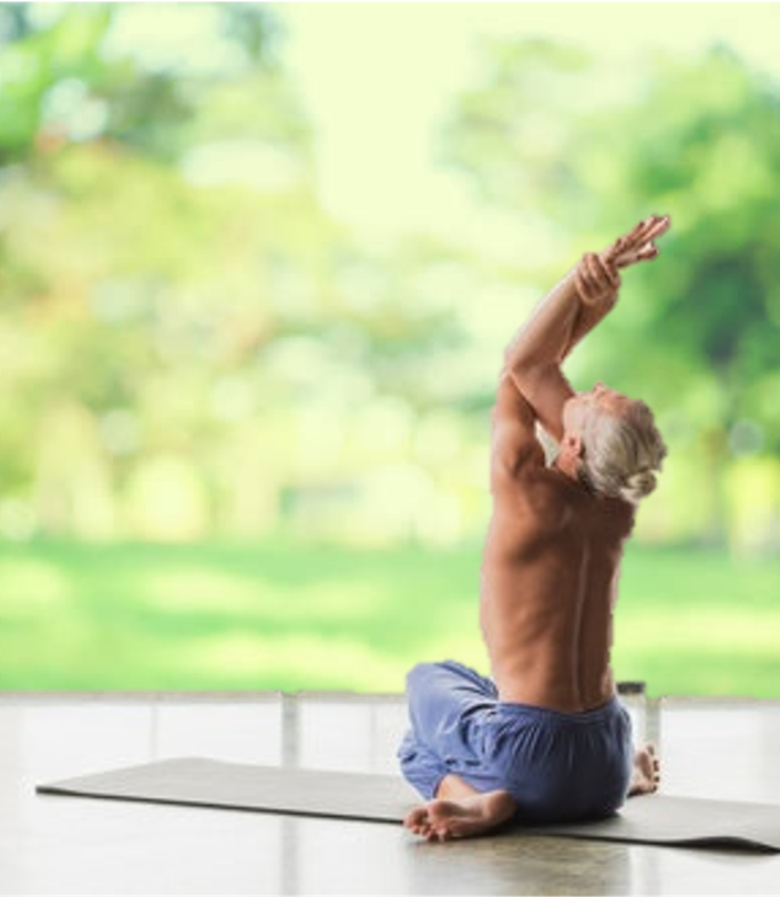Homme senior torse nu en posture d’étirement sur un tapis, dans un cadre naturel lumineux, illustrant la détente musculaire et articulaire par le massage Shiatsu – Cabinet Terre de Shiatsu Lyon 5e