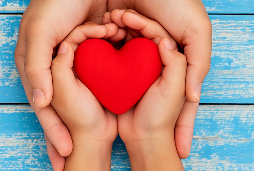 Des mains d'adulte soutenant avec bienveillance des mains d'enfant dans lesquelles se trouve un coeur, illustrant la relation de confiance au cabinet terre de shiatsu Lyon 5e