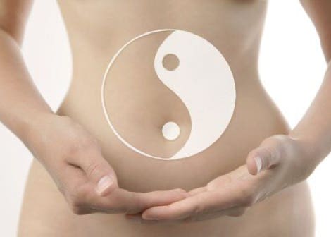Une femme porte entre ses mains le signe taoiste du yin et du yang au niveau de son ventre eprésentant les origines et histoires du massage Chi Nei Tsang - cabinet Terre de Shiatsu Lyon 5e