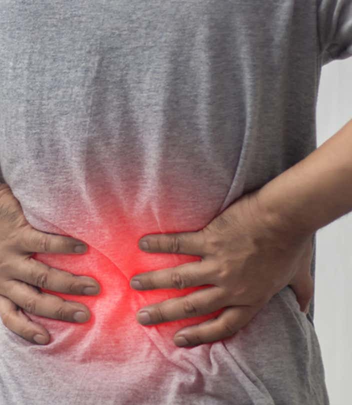 Homme posant ses mains sur le bas de son dos en souffrance, illustrant une douleur lombaire localisée par une lueur rouge, symbole de tension musculaire ou d’inflammation - Cabinet Terre de Shiatsu Lyon 5e