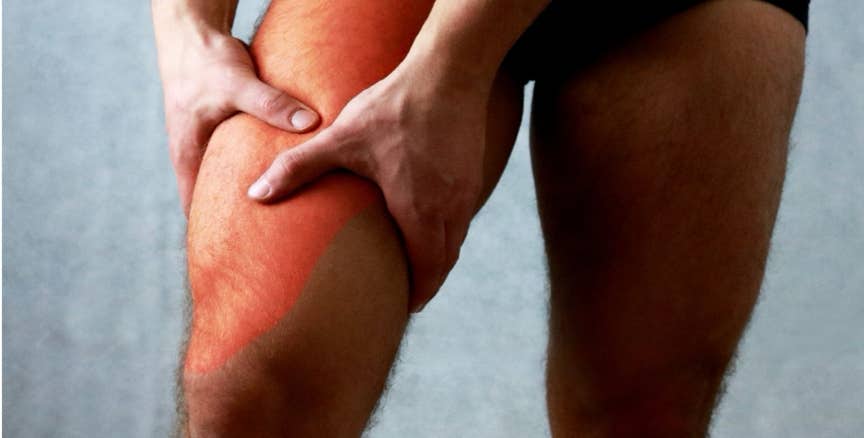 Homme tenant sa cuisse avec les deux mains, une zone rougeoyant indique une douleur musculaire, illustrant les tensions localisées que le shiatsu peut soulager efficacement - Cabinet Terre de Shiatsu Lyon 5e
