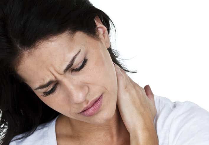 Femme souffrant de douleurs cervicales, posant la main sur son cou avec une expression de tension, illustrant les bienfaits du massage shiatsu pour soulager les douleurs au niveau des cervicales et du haut du dos - Cabinet Terre de Shiatsu Lyon 5e