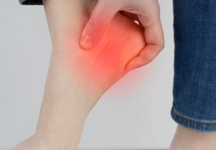 Main massant un talon douloureux avec zone rouge indiquant une inflammation localisée, illustrant les bienfaits du shiatsu pour soulager une épine calcanéenne et améliorer la posture globale - cabinet Terre de Shiatsu Lyon 5e