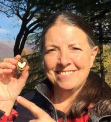 Portrait de Monserrat Gascon souriante et montrant avec son index gauche un petit cercle contenant un coeur qu'elle tient entre le pouce et index de la main droite, illustrant les origines et histoire de la libération du péricarde - cabinet Terre de Shiatsu Lyon 5e