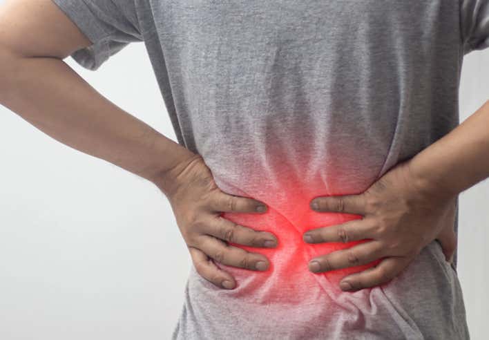 Homme posant ses mains sur le bas de son dos en souffrance, illustrant une douleur lombaire localisée par une lueur rouge, symbole de tension musculaire ou d’inflammation - Cabinet Terre de Shiatsu Lyon 5e