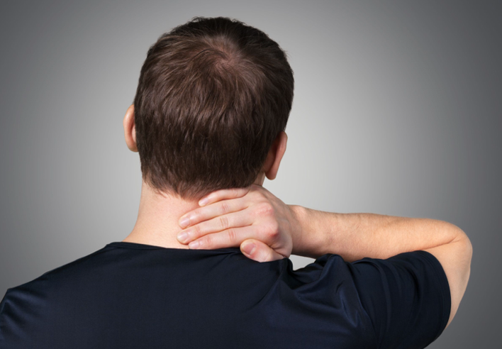 Homme vu de dos tenant sa nuque avec la main, illustrant une douleur cervicale typique du torticolis, en lien avec les bienfaits d’un massage shiatsu pour soulager la contracture - Cabinet Terre de Shiatsu Lyon 5e