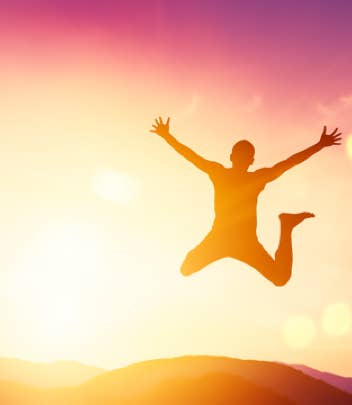Une personne pleine de vitalité et d’énergie sautant à contre-jour dans un coucher de soleil à la montagne avec des couleurs dégradées du jaune lumineux au violet apaisant – cabinet Terre de Shiatsu Lyon 5e
