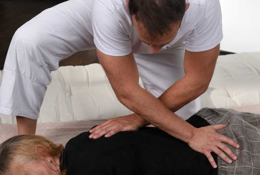 Jérôme Casadebaig pratiquant au sol des pressions adaptées pour soulager les tensions du dos d'un patiente au cabinet Terre de Shiatsu Lyon 5e
