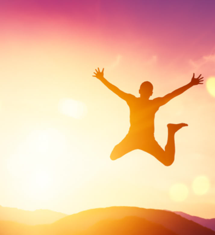 Une personne pleine de vitalité qui saute dans un décor de coucher de soleil en contre-jour en montagne – cabinet Terre de Shiatsu Lyon 5e