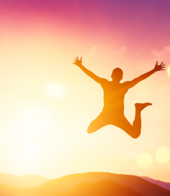 Une personne pleine de vitalité et d’énergie sautant à contre-jour dans un coucher de soleil à la montagne avec des couleurs dégradées du jaune lumineux au violet apaisant – cabinet Terre de Shiatsu Lyon 5e